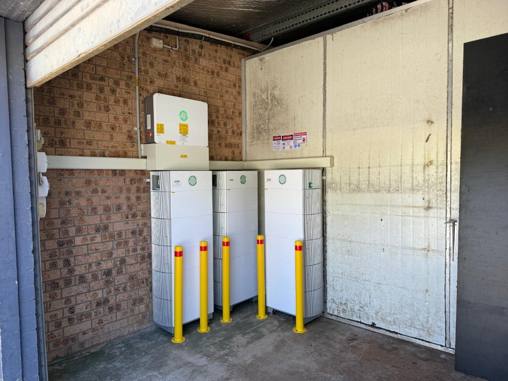 Sungrow battery stacks and wall inverter in commercial garage with safety bollards